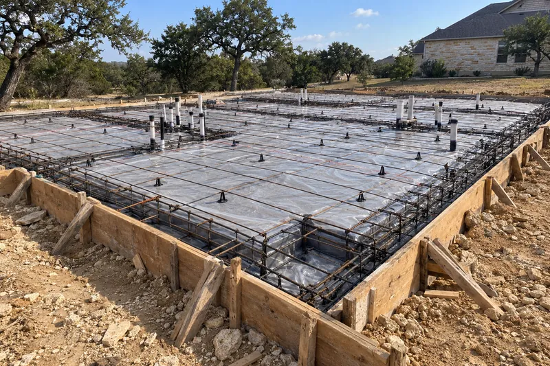 Concrete Contractor in Mount Calm, TX, example photo: formed house slab with plumbing stubs and a plastic vapor barrier, ready for the pour