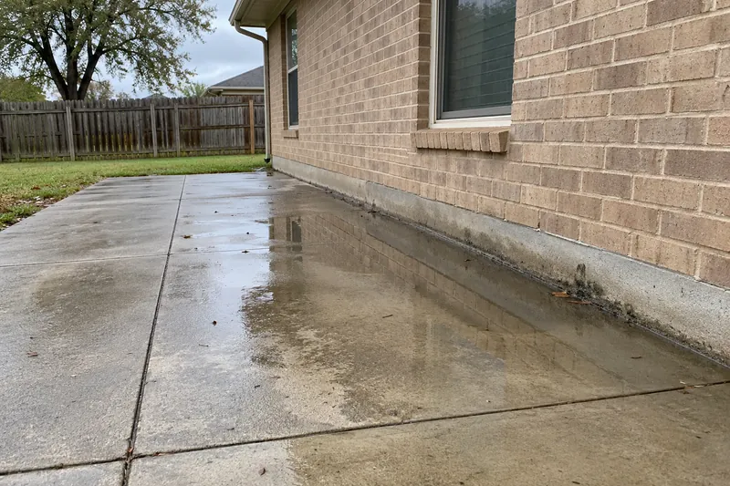 Concrete Leveling in Aquilla, TX, example photo: settled patio tilted toward a house with standing water