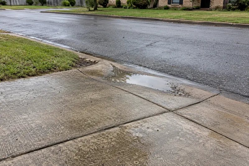 Concrete Leveling in China Spring, TX, example photo: sunken driveway apron with water standing at the low corner