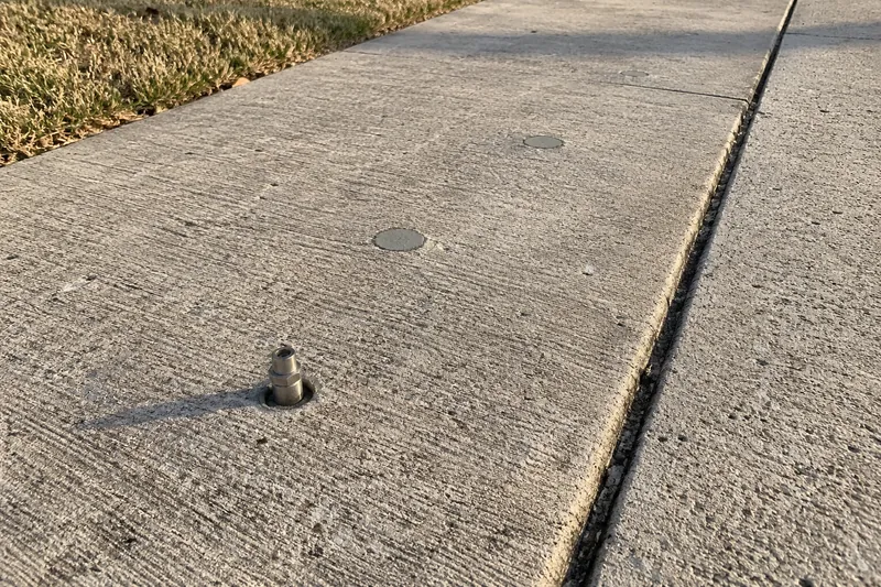 Concrete Leveling in Mosheim, TX, example photo: injection port in a drilled hole in a sunken driveway panel