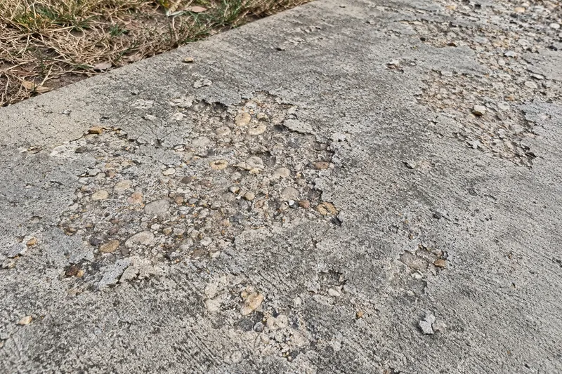 Concrete Repair in Ross, TX, example photo: scaled concrete surface flaking off to show the stone underneath